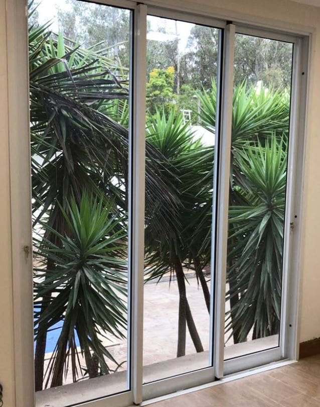 Porta de vidro de correr com esquadria branca em residência — Gravataí/RS
